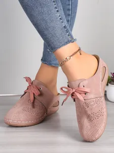 Vue détaillée des mules compensées rose poudré avec motifs découpés au laser et lacets