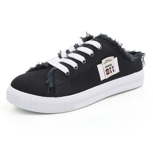 Zapatillas tipo mule de lona negra para mujer con bordes deshilachados y cordones.