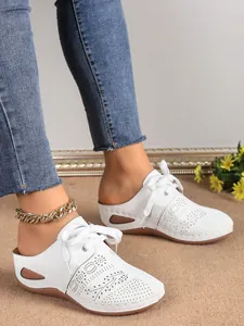 Détail de baskets mules à semelles compensées blanches perforées avec lacets et bracelet