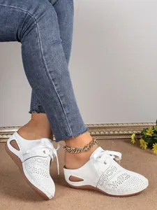 Vue détaillée de mules à talons compensés blanches perforées avec lacets décoratifs