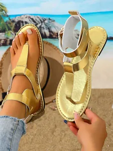 Detailansicht goldener Zehenstegsandalen für Damen mit doppelten Schnallen am Strand