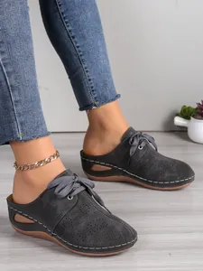 Vue détaillée de mules compensées grises à découpes laser avec un jean décontracté