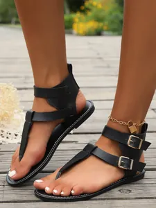 Nahaufnahme schwarzer Zehentrenner-Sandalen mit doppelten Schnallenriemen am Knöchel