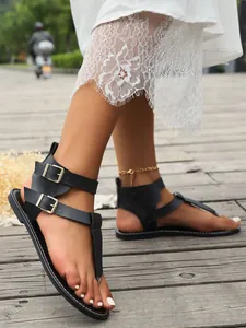 Detailansicht schwarzer Zehensandalen mit Doppelschnallen und Spitzenbesatz