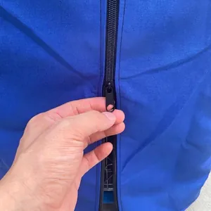 Close-up detail of the durable black zipper on a blue waterproof birdcage cover