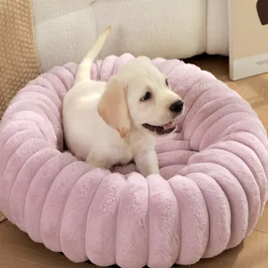 Détail d'un lit rond en peluche rose pour animaux de compagnie avec un chiot confortable