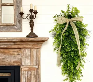 Decorative teardrop eucalyptus swag with a large burlap bow on a white plank wall