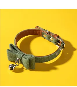Detail view showing the felt texture and silver bell of the green bow pet collar.