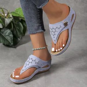 Dettaglio di sandali infradito con zeppa azzurri con eleganti motivi floreali tagliati a laser.