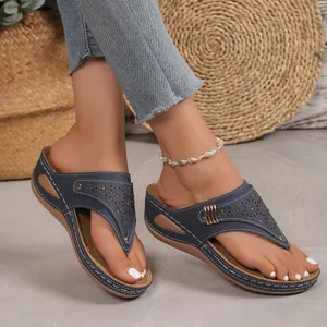 Dettaglio dei sandali con zeppa blu navy con motivi traforati al laser e cuciture.