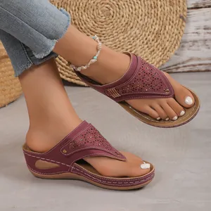 Infradito con zeppa color vinaccia e decorazioni floreali indossati ai piedi