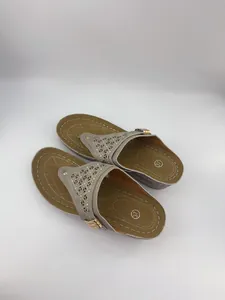 Dettaglio di sandali infradito con zeppa grigi con motivi traforati al laser e borchie.