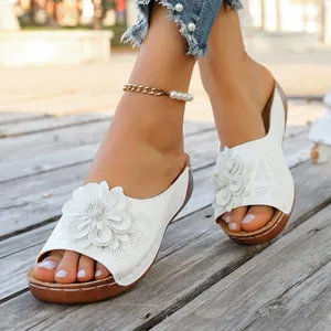 Detail of white women's wedge sandals with large decorative flower ornament