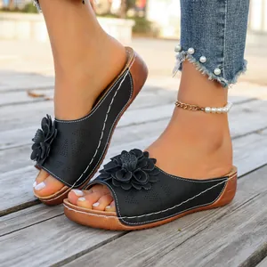 Close-up of black women's wedge sandals with decorative flower and white stitching