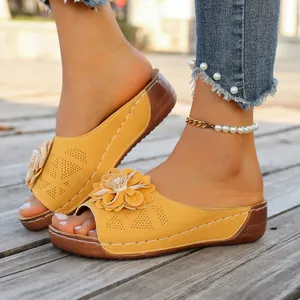 Close-up of yellow flower wedge sandals with perforated details on wooden deck