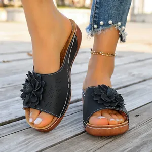 Detailed view of women's black flower slide sandals with platform sole on model's feet