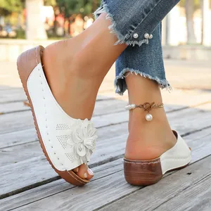 Detailed view of white platform slide sandals featuring a 3D floral accent and wood-textured heel