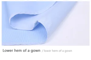 Macro view of the precision-stitched lower hem on a light blue striped dress shirt