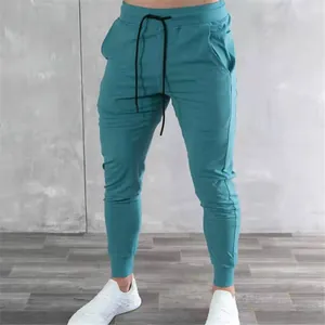 Detail view of teal slim fit men's joggers with black drawstring and cuffed ankles