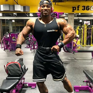 Bodybuilder che posa in palestra con pantaloncini sportivi neri a rete e strisce bianche
