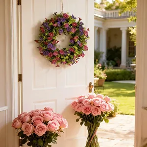 Corona decorativa de petunias artificiales moradas y rosas en una puerta blanca clásica