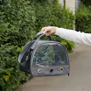 Detail of a grey portable bird carrier with clear PVC window being carried outdoors
