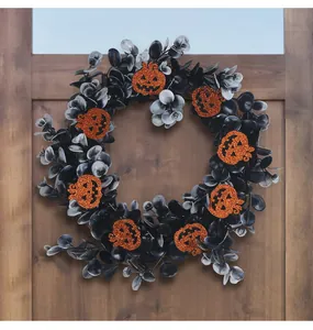 Halloween wreath detail with black leaves and orange glitter pumpkins on wooden door