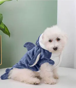 Side view of a small white dog wearing a warm blue plush shark-themed pet outfit.