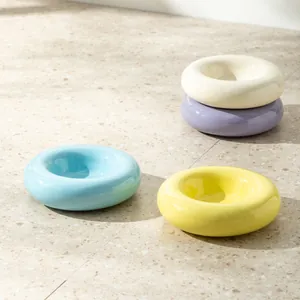 Moderne Keramik-Futternäpfe in Donutform in verschiedenen Pastellfarben auf Terrazzo