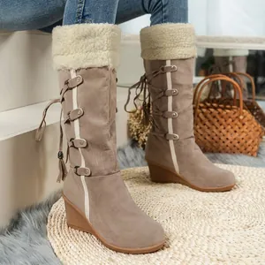 Detail of tan mid-calf boots with lamb wool cuffs and tassel lace-up wedge heels.