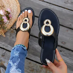 Close-up view of black flat sandals featuring a stylish golden metal buckle on a deck.