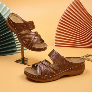 Detail view of brown wedge sandals with cutout patterns and white stitching accents
