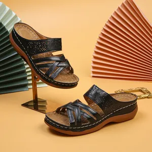 Detail of black wedge sandals with laser-cut patterns and criss-cross straps on yellow background.