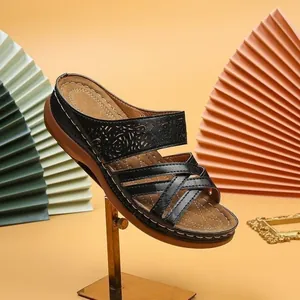 Detailed side view of elegant black wedge sandals with cutout patterns and cross straps
