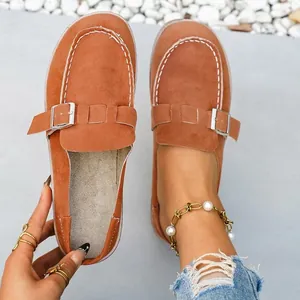 Detail shot of orange suede-like mules with metal buckle and pearl anklet detail.