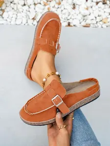 Close-up of orange faux suede mule slippers with a stylish metal buckle detail.