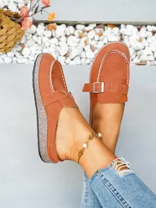 Detail view of women's orange faux suede mules with metal buckle and thick sole