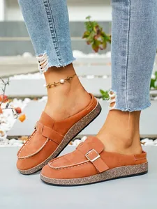 Close-up of brown faux suede clog mules with metal buckle and cork-textured sole