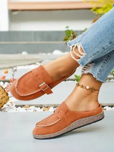 Close-up of orange faux suede closed-toe mules with adjustable metal buckle strap.