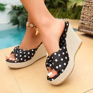 Primer plano de sandalias de cuña de lunares con tacones de paja tejida y lazo.