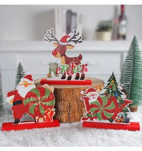 Detailed view of three festive wooden Christmas ornaments on a snowy wooden stump.