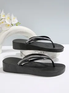 Detailansicht der schwarzen Plateau-Flip-Flops mit glitzernden Strass-Riemen.