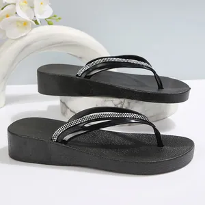 Detailansicht der schwarzen Plateau-Flip-Flops mit funkelnden Strassriemen für Damen