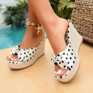Primer plano de sandalias con cuña de lunares blancos, tacón de esparto y lazo