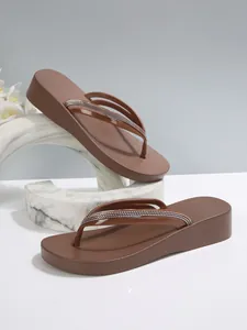 Detailansicht der braunen Plateau-Flip-Flops mit glitzernden Strassriemen für Damen