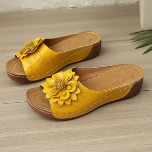 Nahaufnahme von gelben Keilsandaletten mit Blumenornament und Lochmuster-Design.