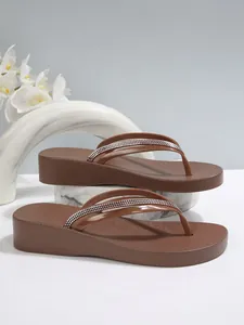 Detailansicht der braunen Plateau-Flip-Flops für Damen mit funkelnden Strassriemen.