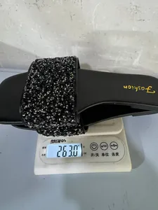Dettaglio di un sandalo nero con strass che mostra un peso di 263g su una bilancia