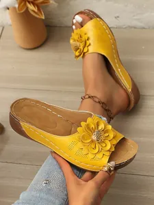 Detail einer gelben Keilsandale mit 3D-Blumendekor und hohlem Design-Stil