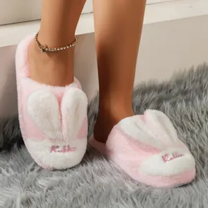 Detailed close-up view of cute pink plush rabbit ear slippers on a soft grey rug